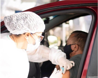 Idoso recebendo a vacina sentado em banco de carro