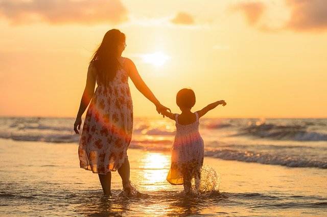 Mãe e filho em uma praia no momento do pôr-do-sol
