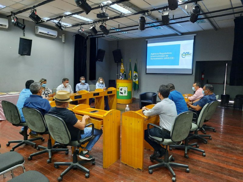 Pessoas reunidas em uma sala com projetor ao fundo.