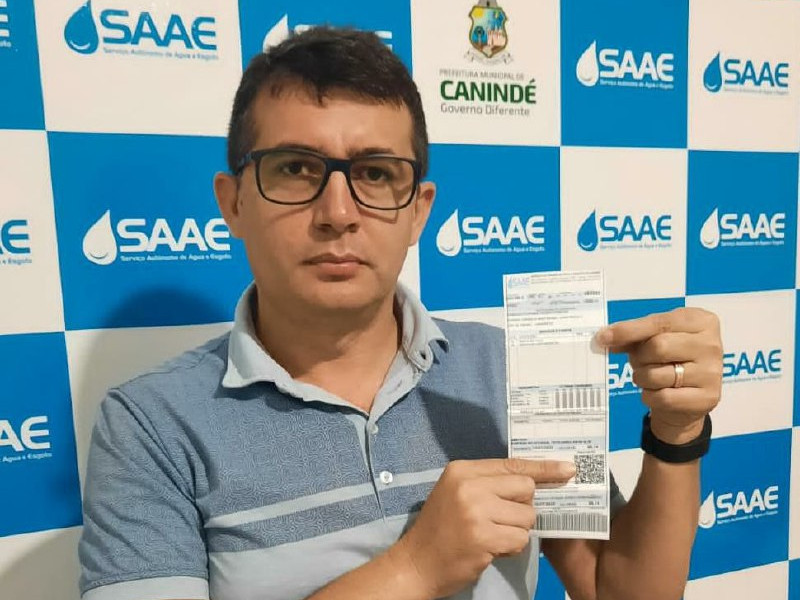 Homem segurando papel da conta do saae que pode ser pago pelo pix