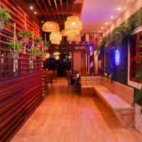 Entrada do Bar do Zé, com decoração em madeira, luminárias e plantas.