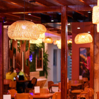 Bar do Zé. Espaço com mesas e cadeiras de madeiras, decorado com luzes pendentes