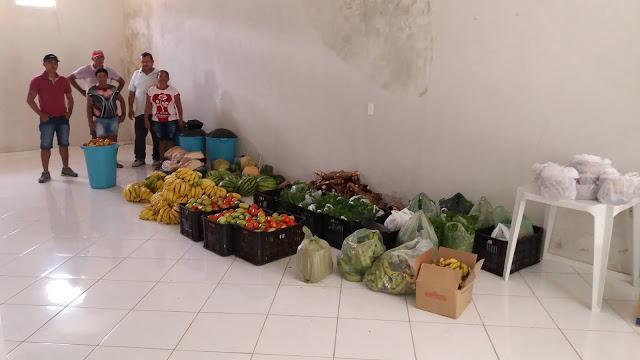 Tr&ecirc;s homens e duas mulhres e a frente v&aacute;rias frutas e legumes