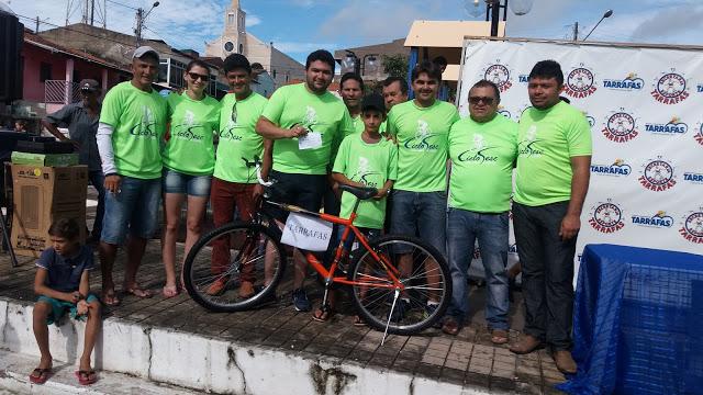 Prefeito posa para foto com v&aacute;rias pessoas e o ganhador da bicicleta