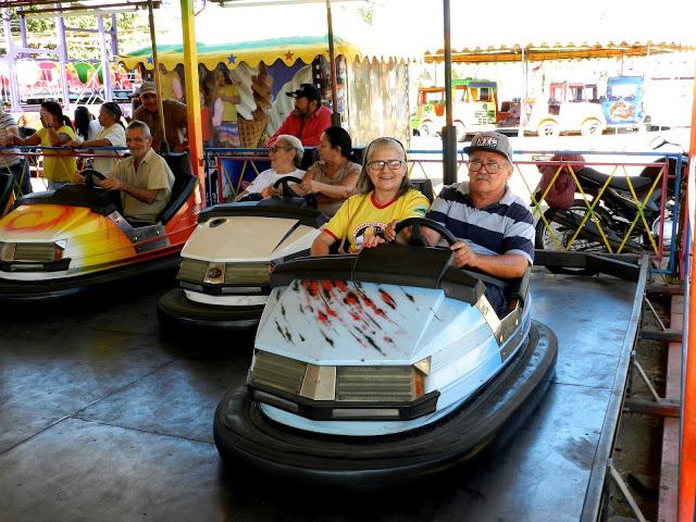 Idosos em carrinho no parque de divers&otilde;es.