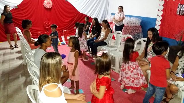 As mamães sentadas e as crianças a em pé a sua frente