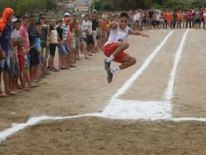 V&aacute;rias pessoas assistindo ao salto do jovem no Atletismo de Tarrafas.