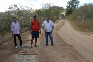 Tr&ecirc;s pessoas numa estrada e um trator ao fundo.