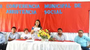 v&aacute;rias pessoas sentadas e uma mulher falando ao microfone