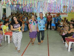 V&aacute;rias pessoas assistindo e aplaudindo dois idoso desfilando.